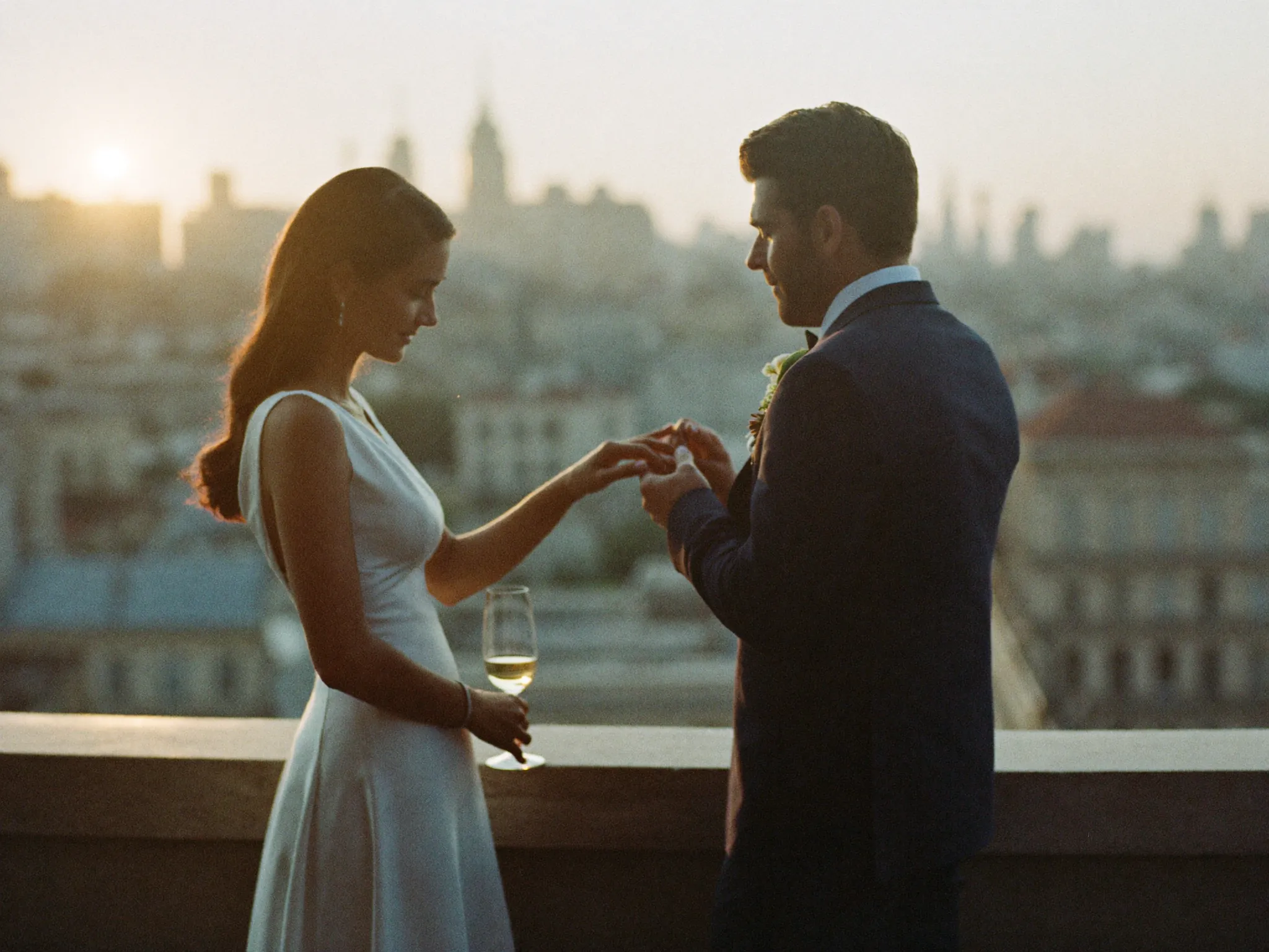 A couple exchanging rings on the terrace as the sun sets over the city