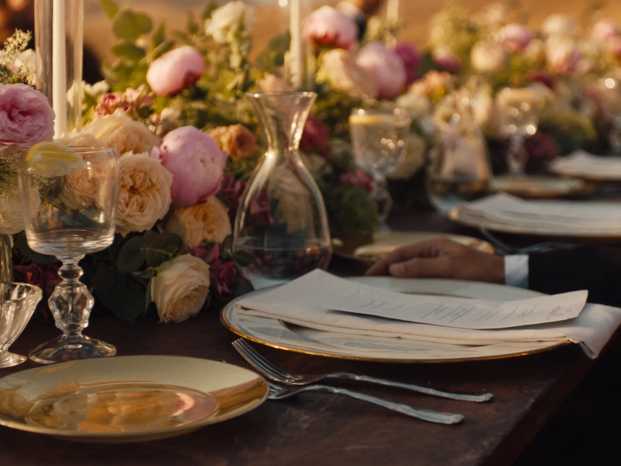 An intimate tablescape with peonies, garden roses and candlelight at dusk