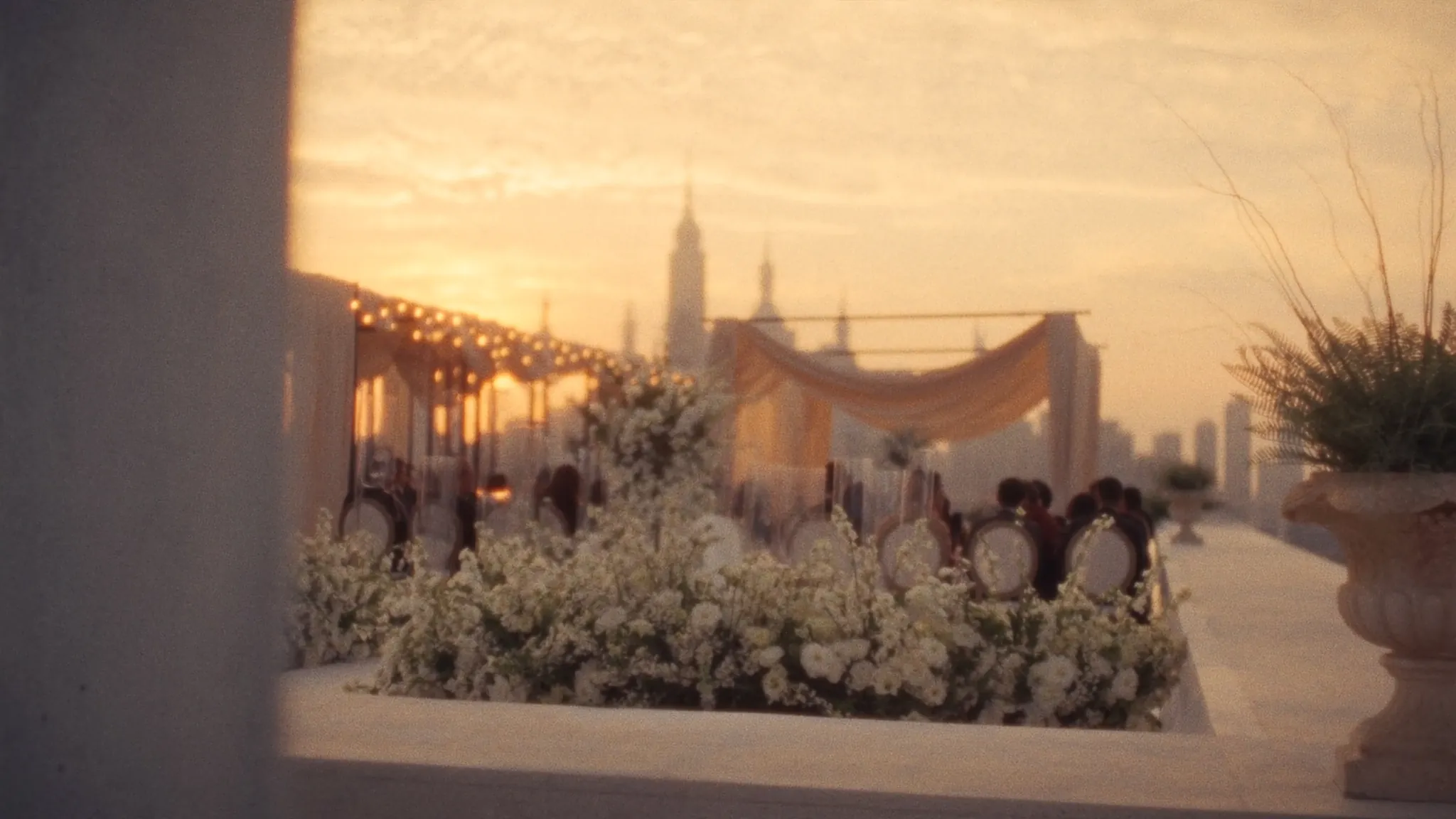 Rooftop terrace dressed with white florals at golden hour, city skyline beyond